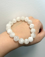 White beaded bracelet on a wrist against a plain background